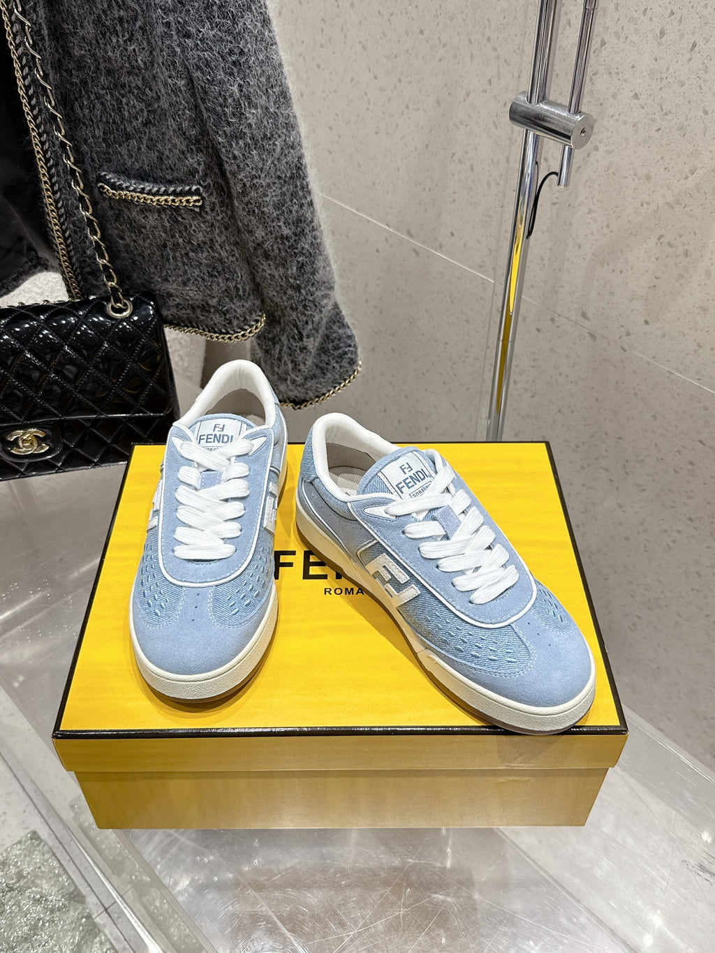 Pair of light blue Fendi sneakers with white laces and F logo on beige soles