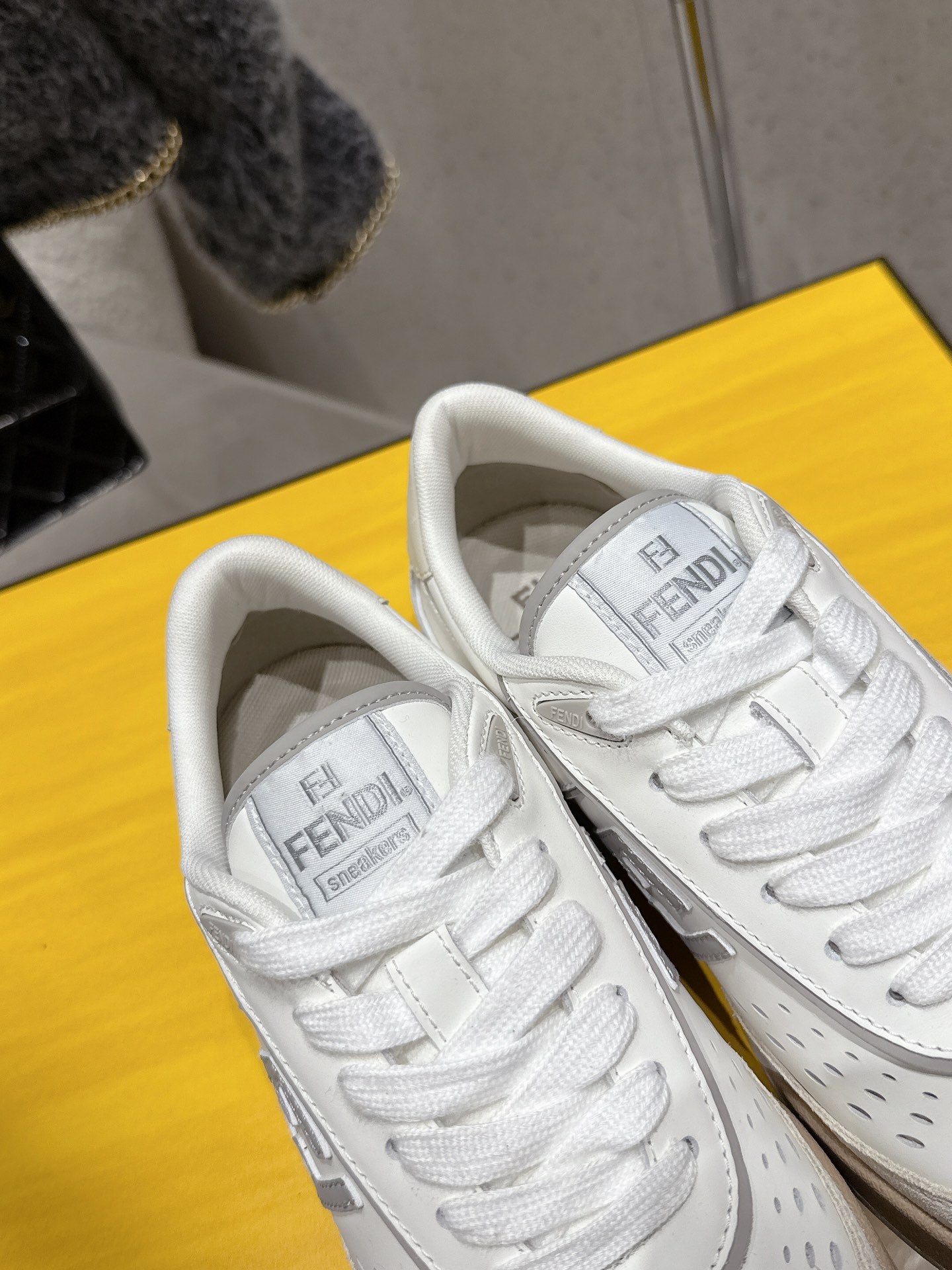 White Fendi sneakers close-up, lace-up front with FENDI Roma tongue
