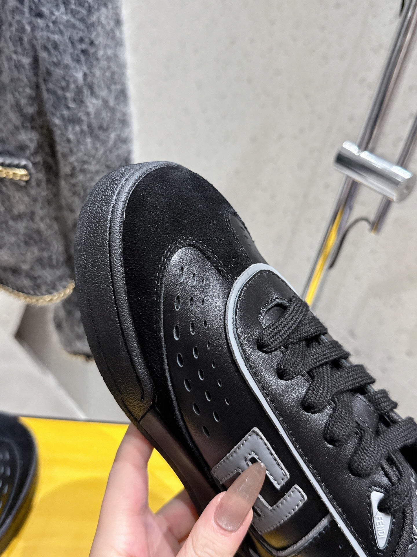 Black Fendi sneaker close-up: perforated toe, laces, and white side logo stripe