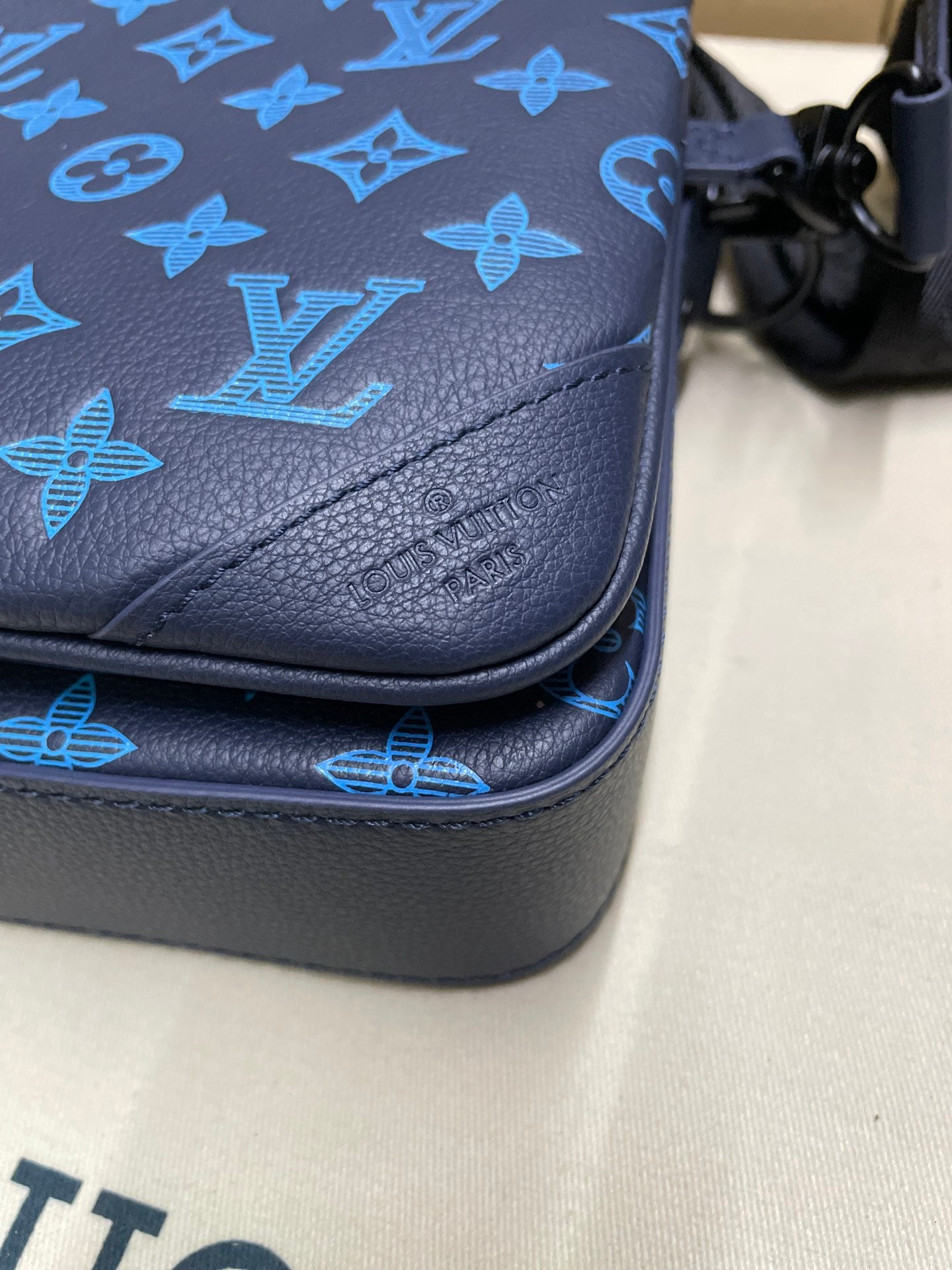 Blue leather crossbody corner with monogram pattern and stitched edge