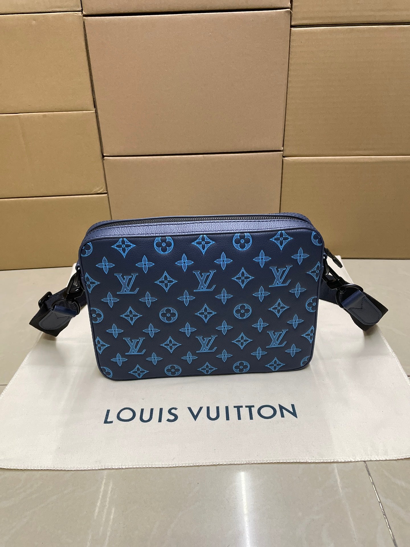 Blue monogram crossbody bag with rounded shape and zipper closure
