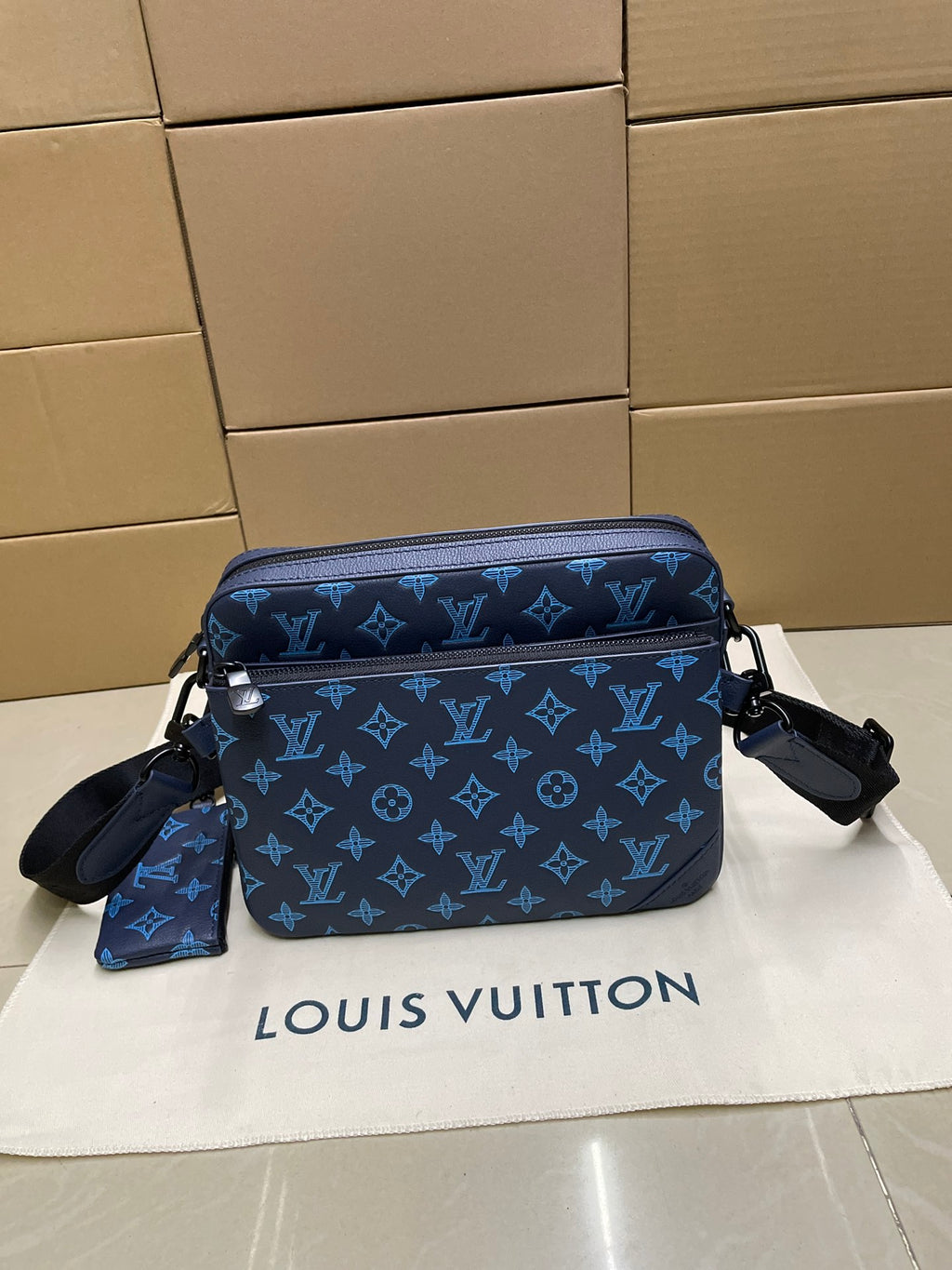 Blue monogram crossbody bag with front flap, dual zippers, and shoulder strap