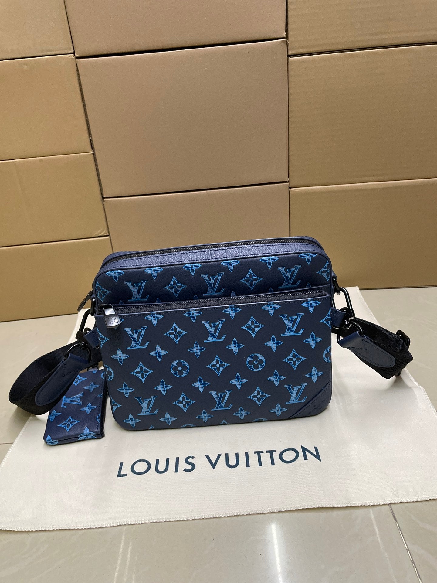 Blue monogram crossbody bag with front flap, dual zippers, and shoulder strap