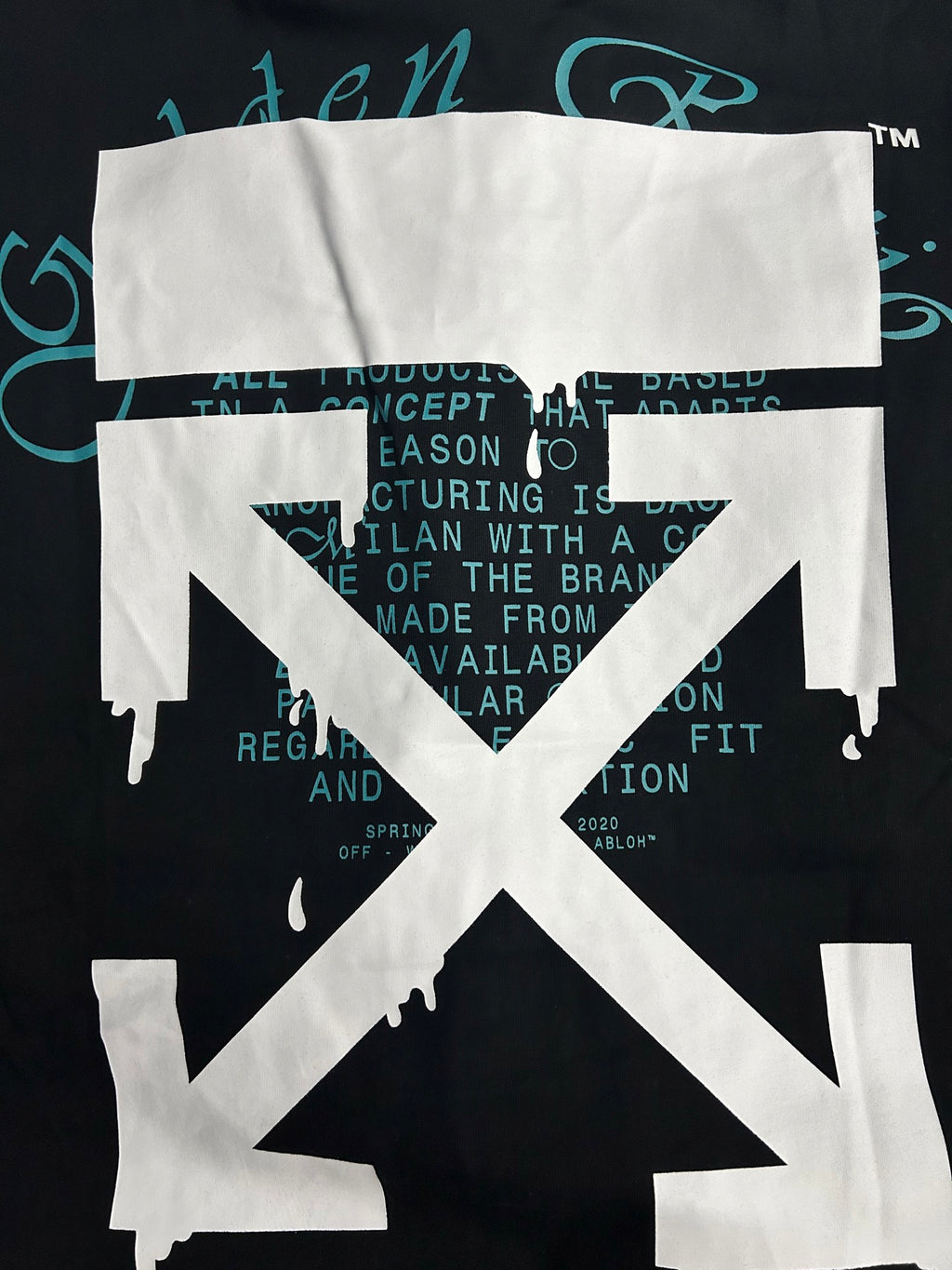 Black graphic T-shirt with white emblem and teal background text behind it.