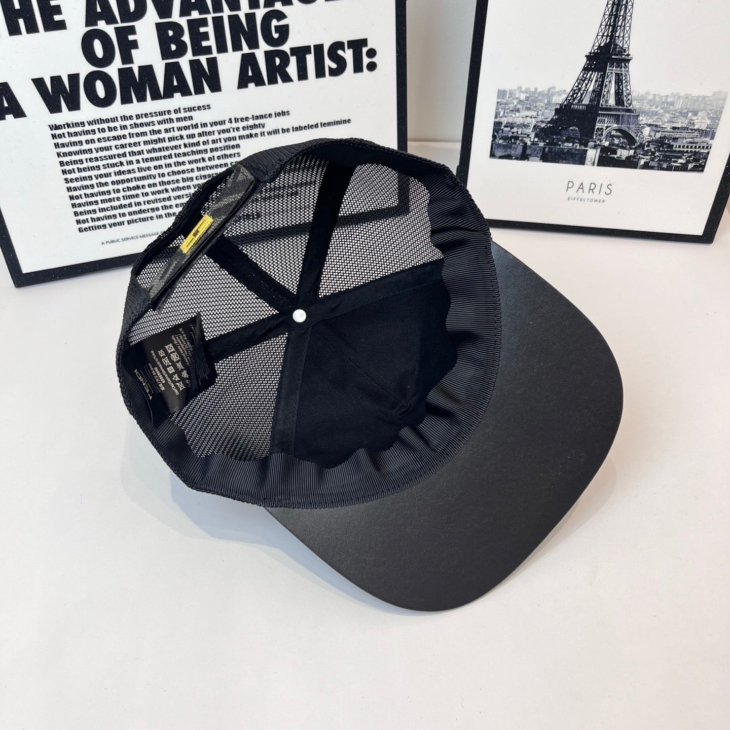 Black mesh baseball cap with yellow logo tag and curved brim