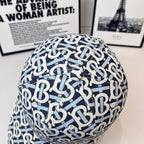 Burberry cap close-up showing navy-and-white B logo pattern across the crown