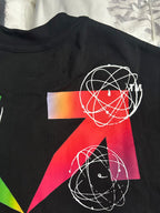Black T-shirt close-up with red and green geometric artwork and white orbit lines