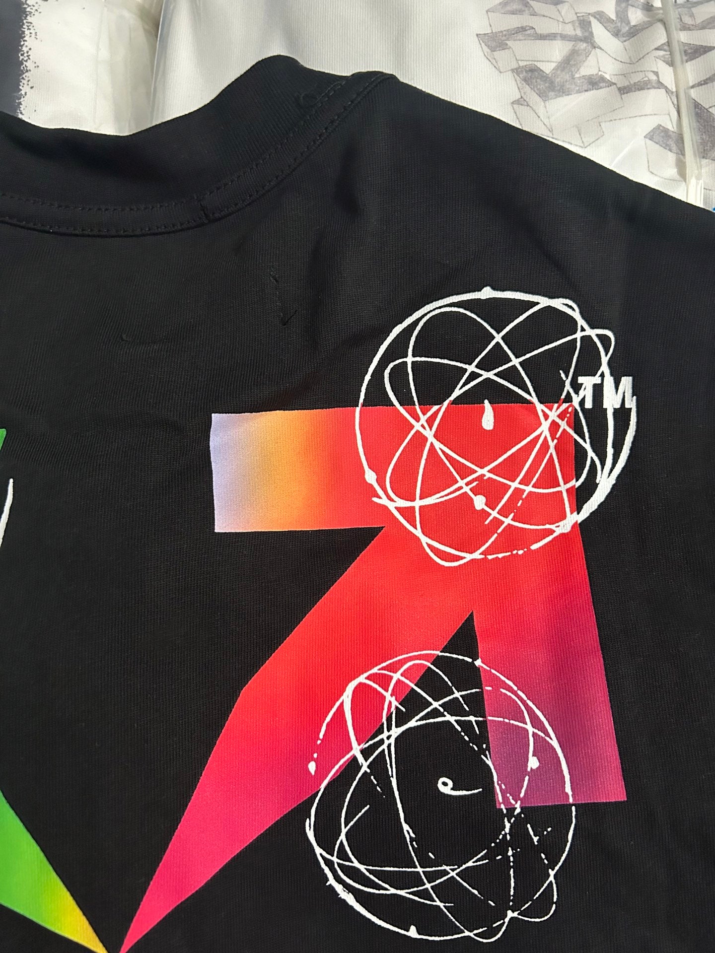 Black T-shirt close-up with red and green geometric artwork and white orbit lines
