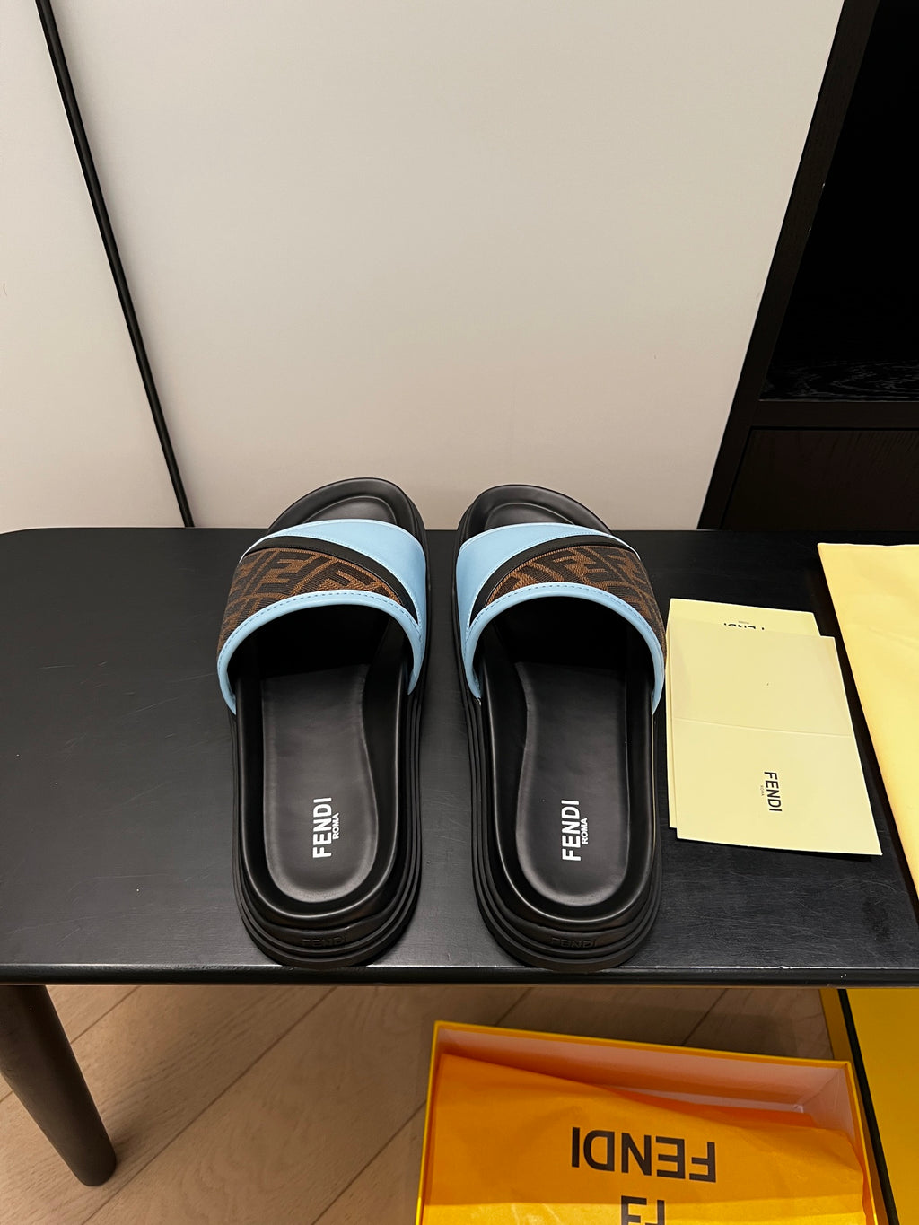 Pair of blue slide sandals with brown FF-logo straps and black rubber soles