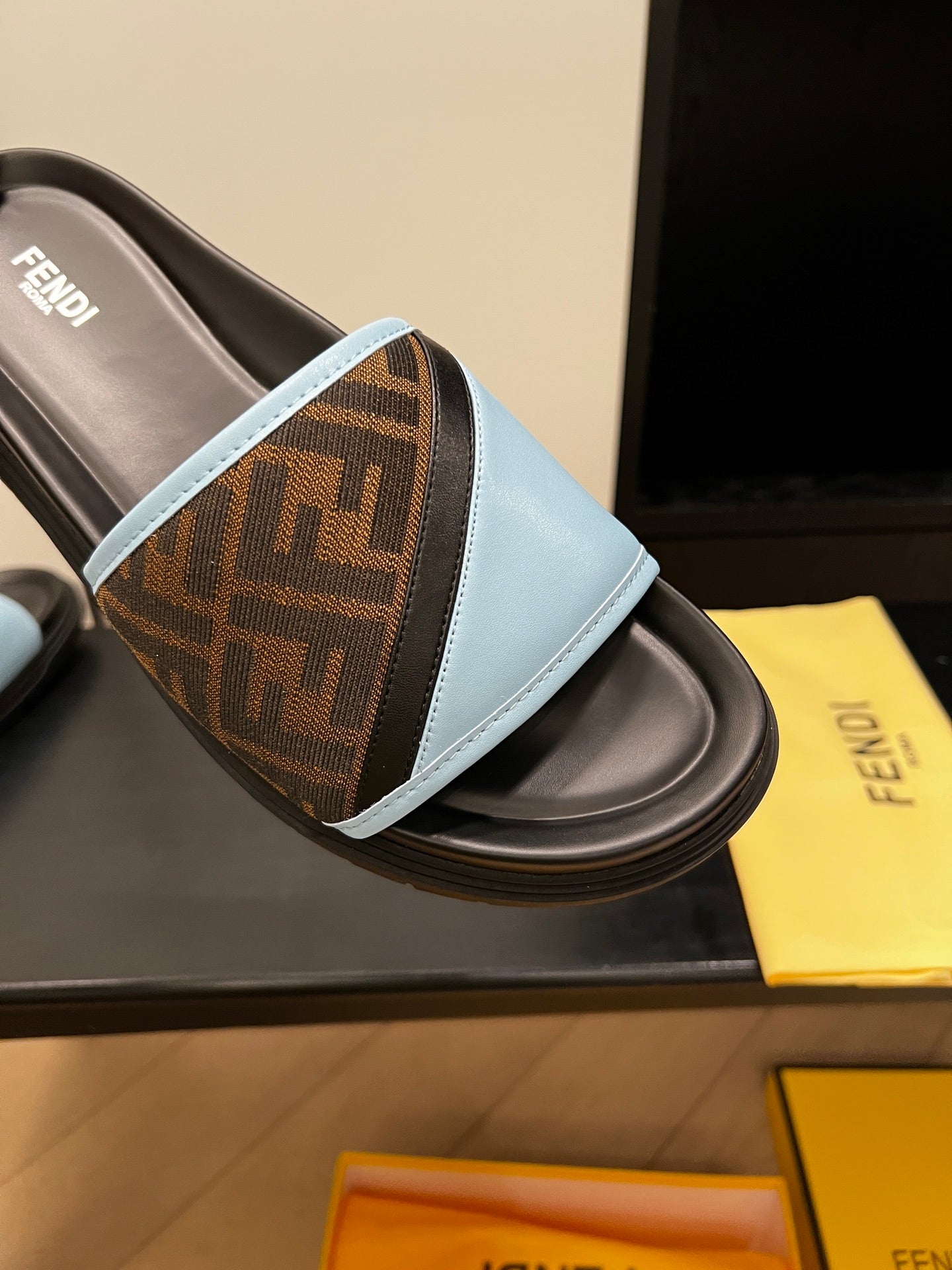 Blue slide sandal detail: brown FF-logo strap with light blue trim on black footbed
