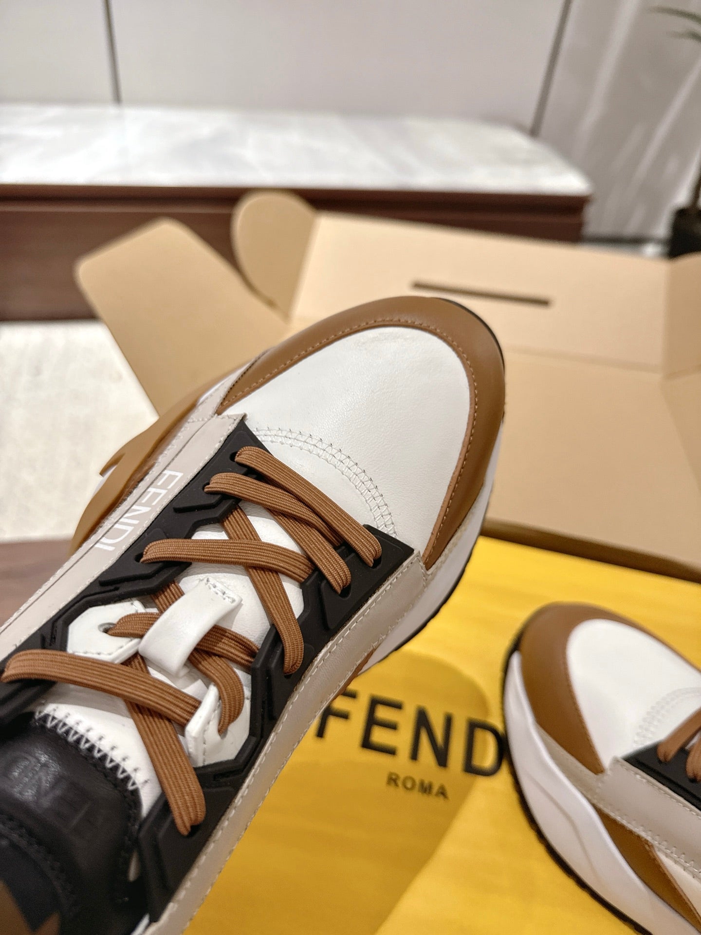 Fendi unisex sneakers side view with brown laces, black panels, and white curved accents