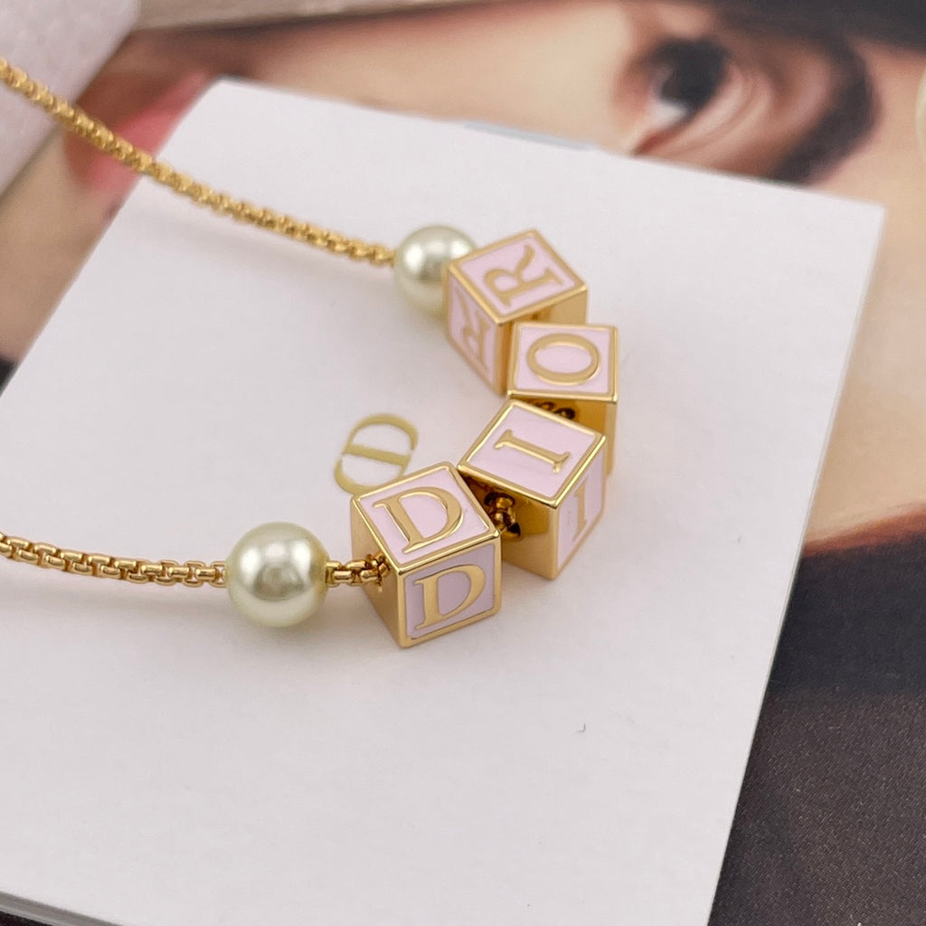 Close-up of gold-tone Dior letter charms with pearl bead on a chain