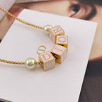 Close-up of gold-tone Dior letter charms with pearl bead on a chain
