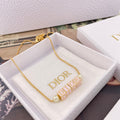 Gold-tone Dior letter necklace with pearl beads on a chain, shown in a box