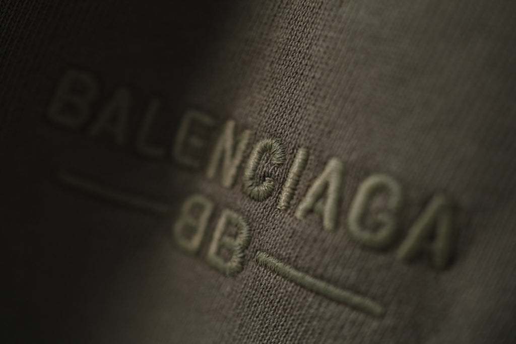 Balenciaga logo embroidery on dark green fabric close-up