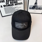 Black baseball cap with Christian Dior Atelier front patch and small top button.