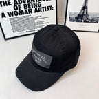 Black baseball cap angled view with Christian Dior Atelier logo patch.