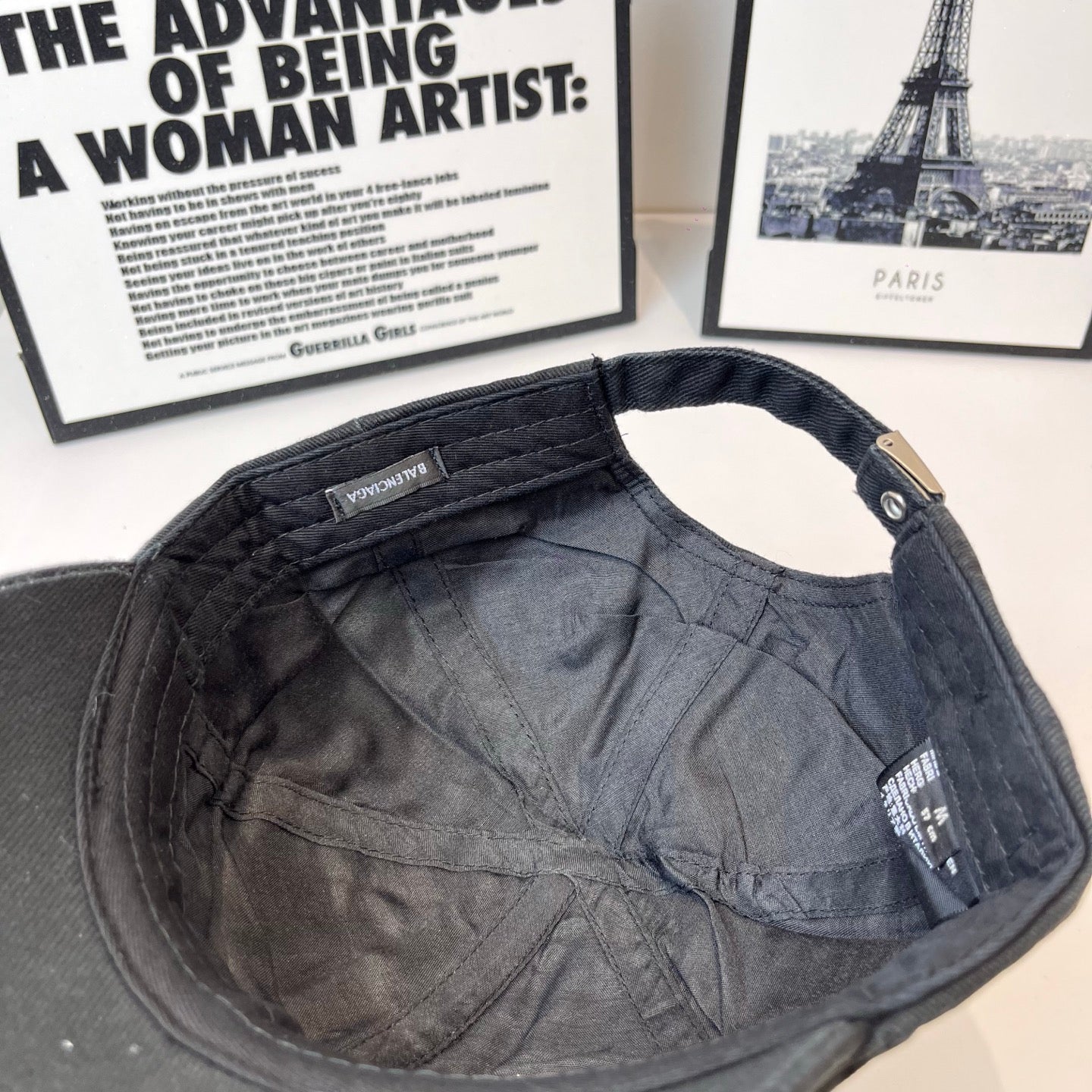 Dark baseball cap interior showing lining and stitched strap panel with tag.