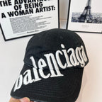 Dark baseball cap with white "balenciaga" logo embroidered on the front.
