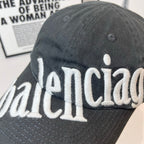 Balenciaga cap close-up in dark gray with large white “balenciaga” embroidered logo