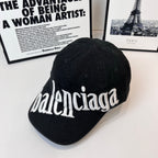 Balenciaga cap with white embroidered “balenciaga” script across the front, dark fabric