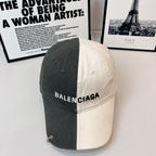Two-tone baseball cap, dark gray and off-white, BALENCIAGA logo on front.