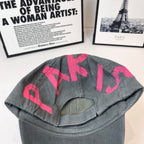 Baseball cap, dark gray with pink letters on back of crown and curved brim.