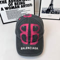 Baseball cap, dark gray with pink graphic logo and BALENCIAGA text on front.