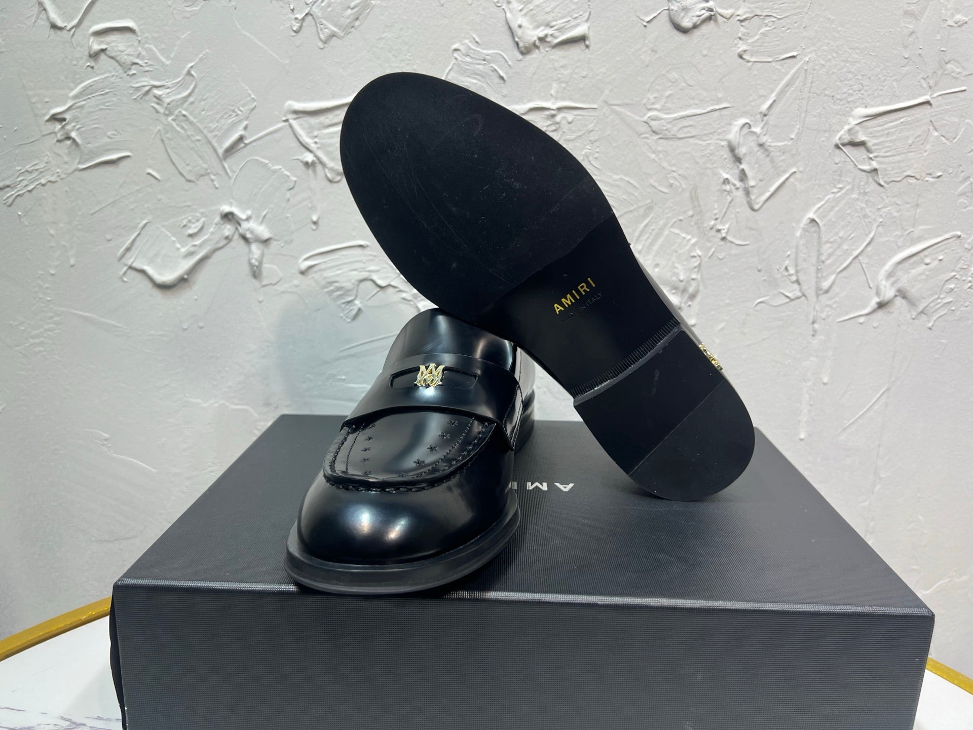 Amiri black leather loafer shoe with gold emblem, shown with outsole and upper