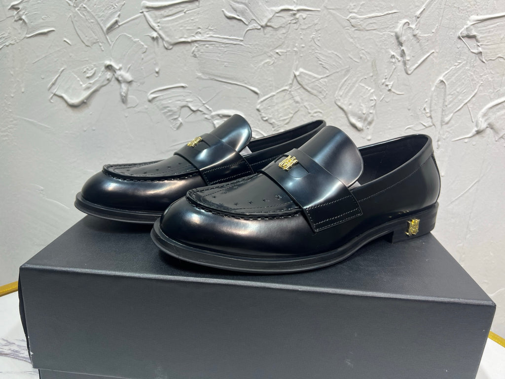 Amiri black leather loafers with gold emblem on strap, side angle view
