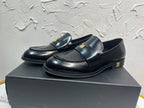 Amiri black leather loafers with gold emblem on strap, side angle view