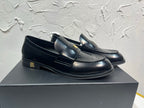 Amiri black leather loafers with gold emblem strap, front three-quarter view