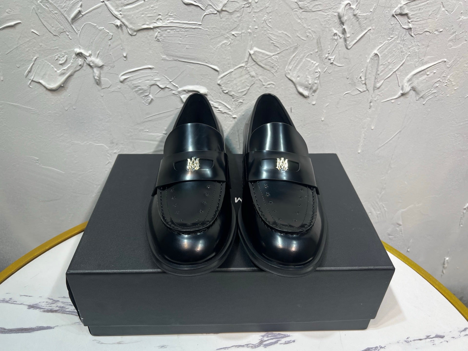 Amiri black leather loafer shoes, penny strap with gold emblem detail, front view