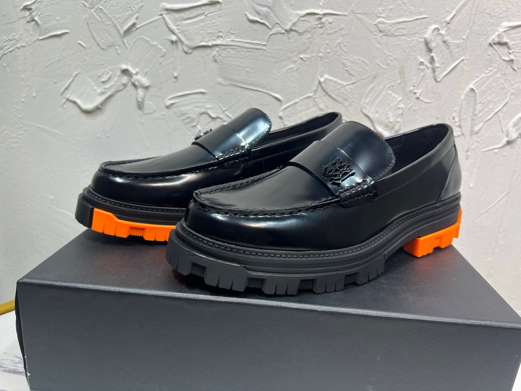 Black leather loafers with orange outsole and metal buckle detail, side view pair