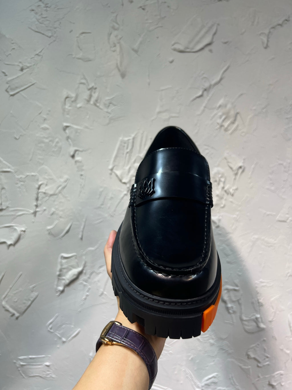 Black leather loafer with orange tread sole, back view single shoe