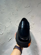 Black leather loafer with orange tread sole, back view single shoe