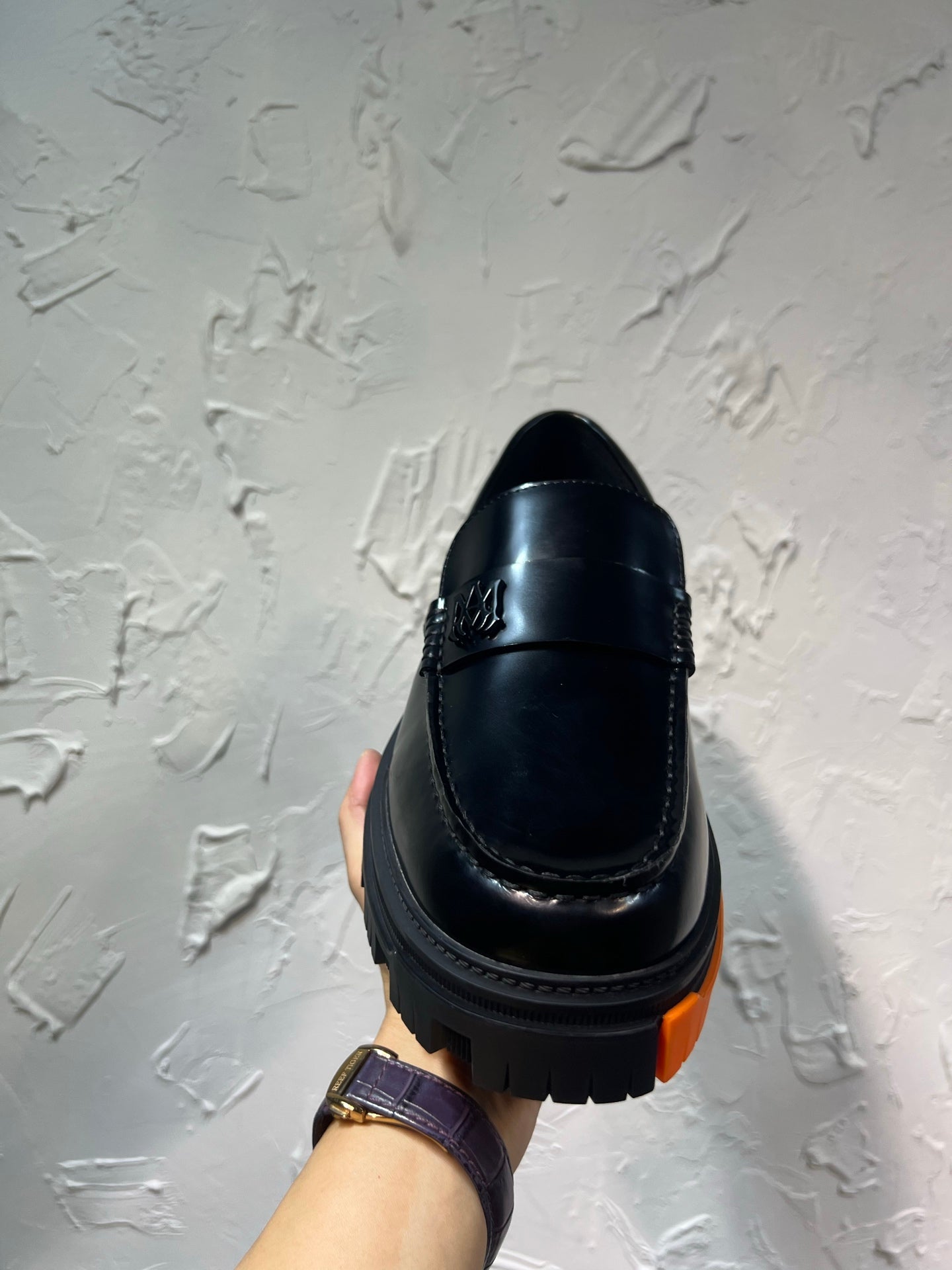 Black leather loafer with orange tread sole, back view single shoe