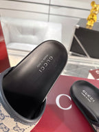 Black Gucci slide sandal showing logo footbed and curved strap
