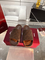 Gucci monogram slide sandals, dark brown with leather-look footbed and wide strap.
