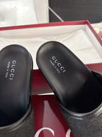 Gucci black slide sandal close-up of footbed with Gucci logo text