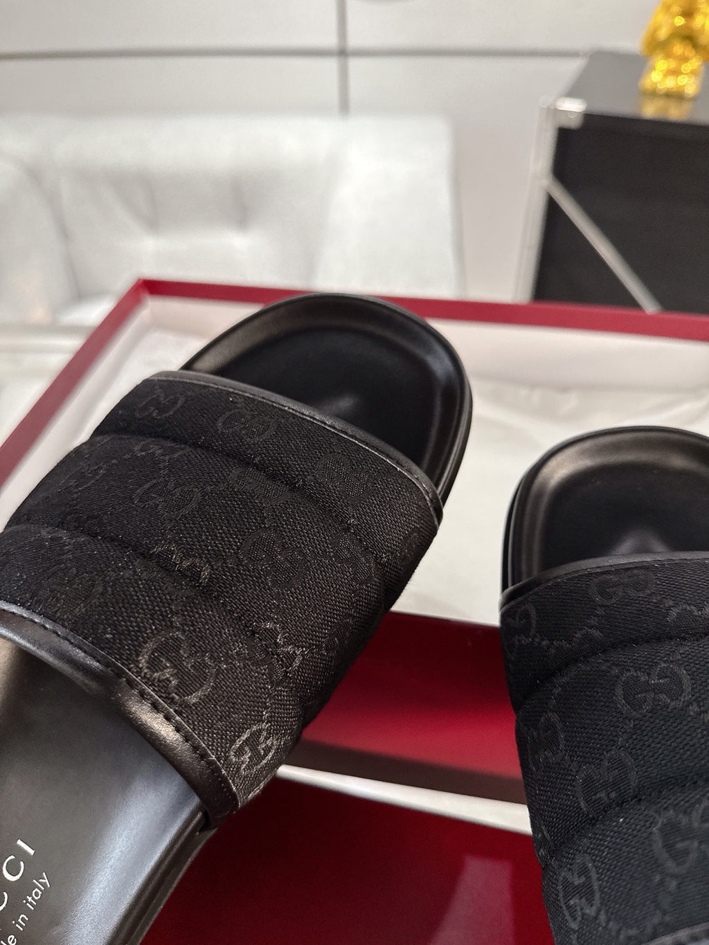 Gucci black slide sandals close-up of monogram strap and stitched edge detail