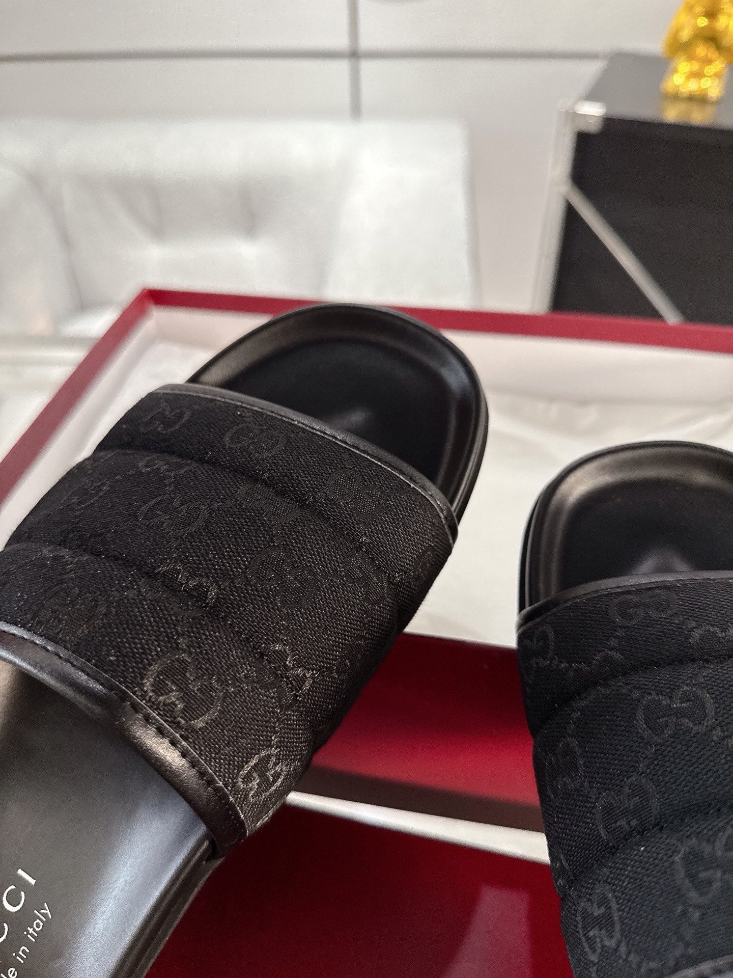 Gucci black slide sandals close-up of monogram strap and stitched edge detail