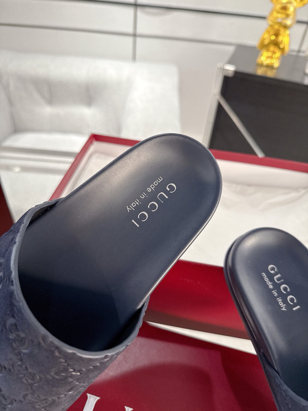 Navy slide sandals close-up: monogram strap and Gucci insole lettering