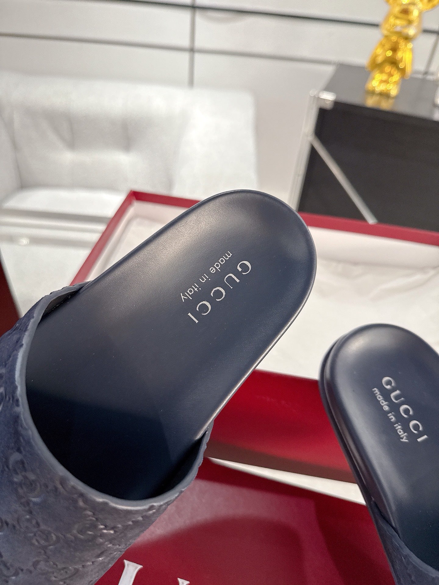 Navy slide sandals close-up: monogram strap and Gucci insole lettering