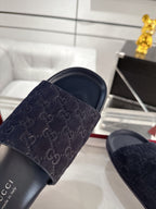 Navy slide sandals close-up: wide monogram strap over dark cushioned footbed