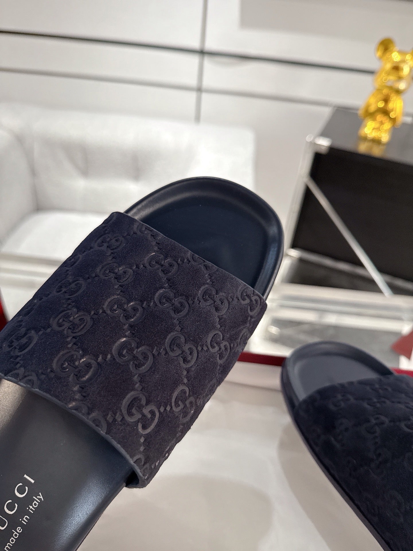 Navy slide sandals close-up: wide monogram strap over dark cushioned footbed