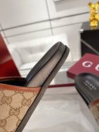 Gucci slide sandal close-up, beige GG canvas strap with black footbed
