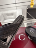 Black Gucci slide sandals close-up of embossed strap edge and Gucci footbed.