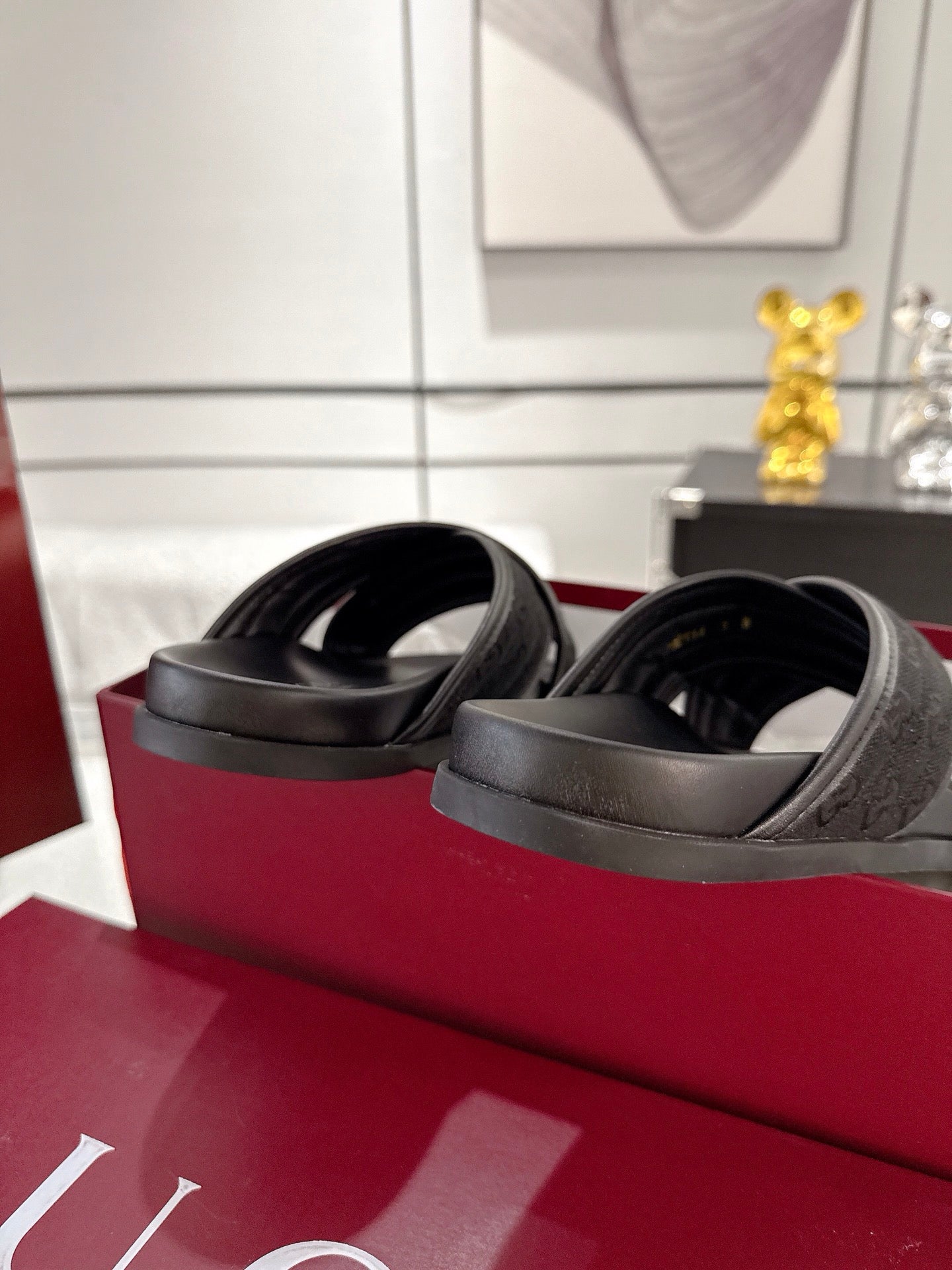 Black Gucci slide sandals side view, embossed strap with thick rubber sole.