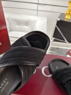 Black Gucci slide sandals close-up of embossed strap and open toe.